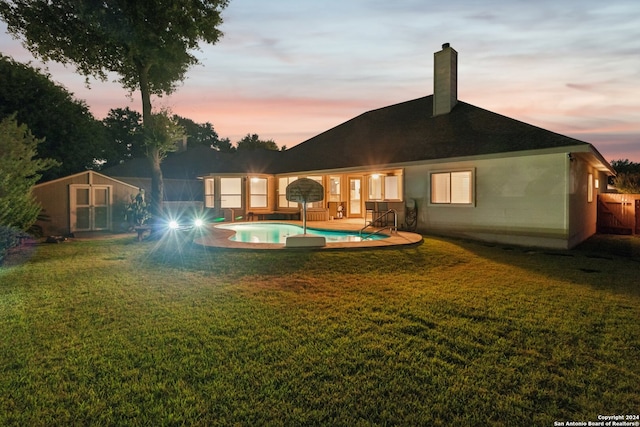 back house at dusk with an outdoor structure and a lawn