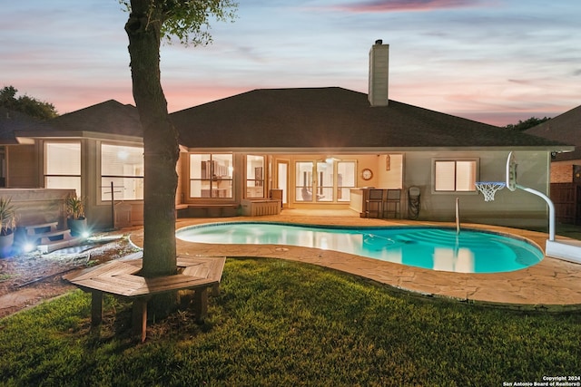 pool at dusk featuring french doors and a patio area