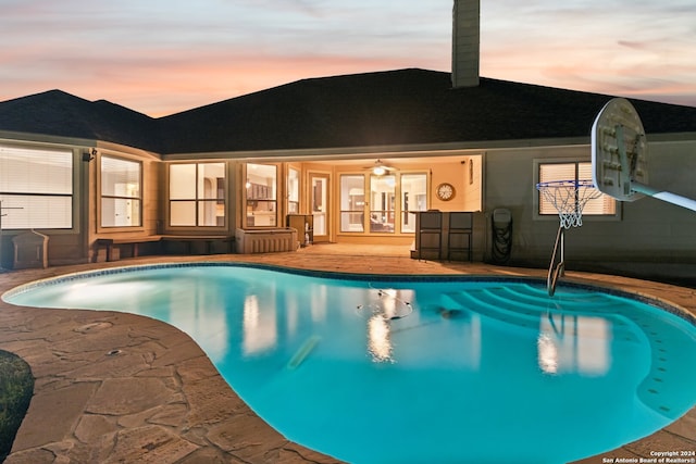 pool at dusk with french doors and a patio area