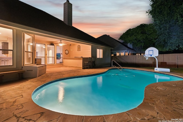 pool at dusk with a patio area