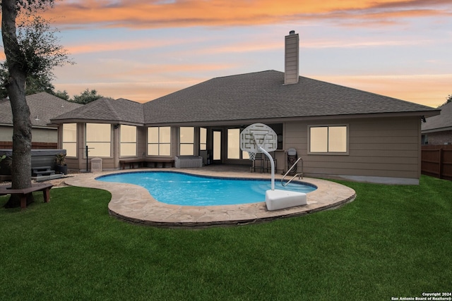 pool at dusk featuring a patio, a yard, a hot tub, and a water slide