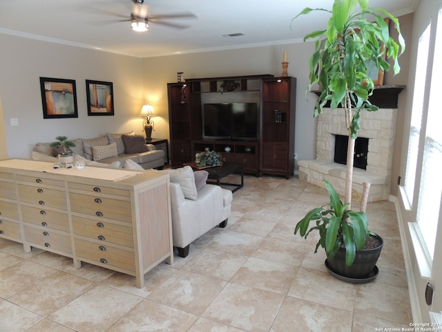 tiled living room featuring ornamental molding, ceiling fan, and a stone fireplace