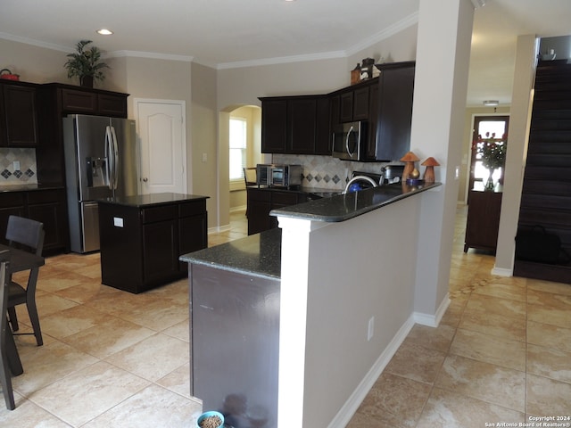 kitchen featuring appliances with stainless steel finishes, backsplash, dark stone counters, and a center island