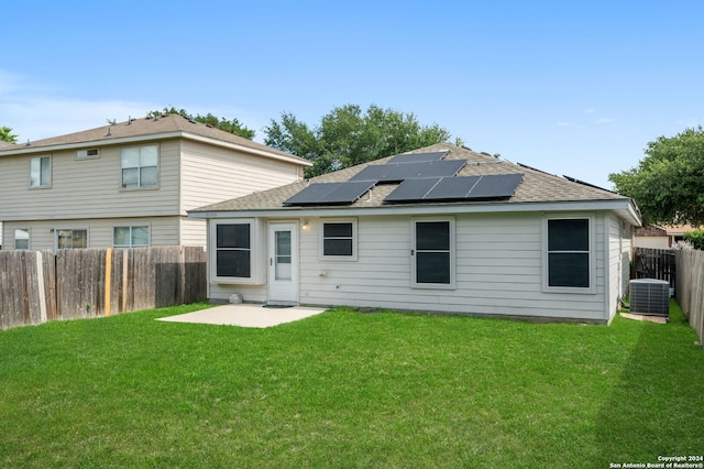 rear view of house with solar panels, a lawn, and a patio