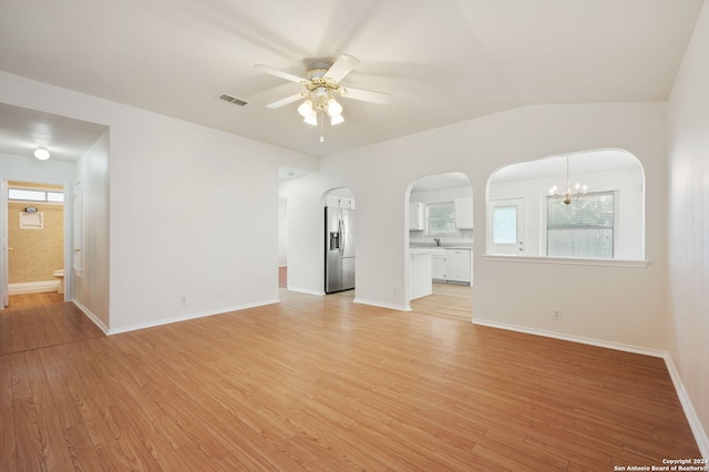 empty room with ceiling fan with notable chandelier, light wood-type flooring, lofted ceiling, and sink