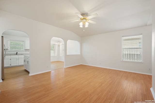 unfurnished living room with lofted ceiling, ceiling fan with notable chandelier, light hardwood / wood-style floors, and sink