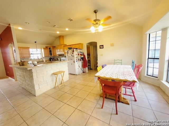 dining space featuring lofted ceiling, light tile patterned flooring, and ceiling fan