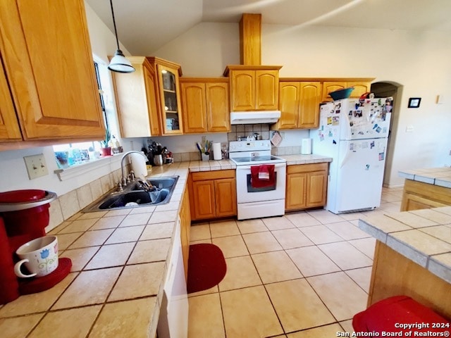 kitchen with lofted ceiling, white appliances, tile counters, and sink