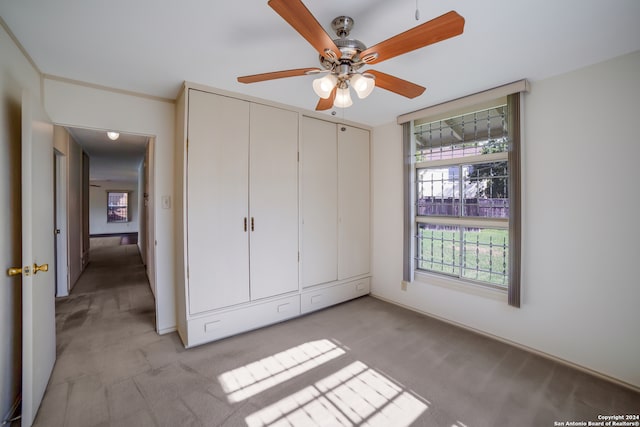 unfurnished bedroom with light carpet, ceiling fan, and a closet