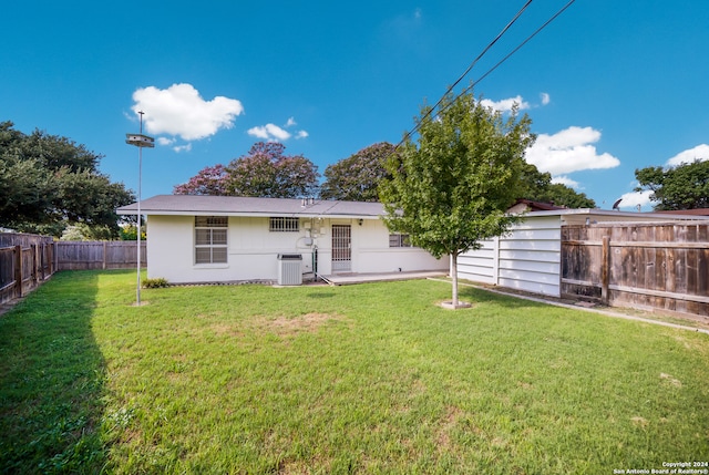 rear view of property featuring a yard and central AC unit