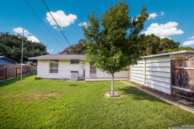 back of property with central AC unit and a yard