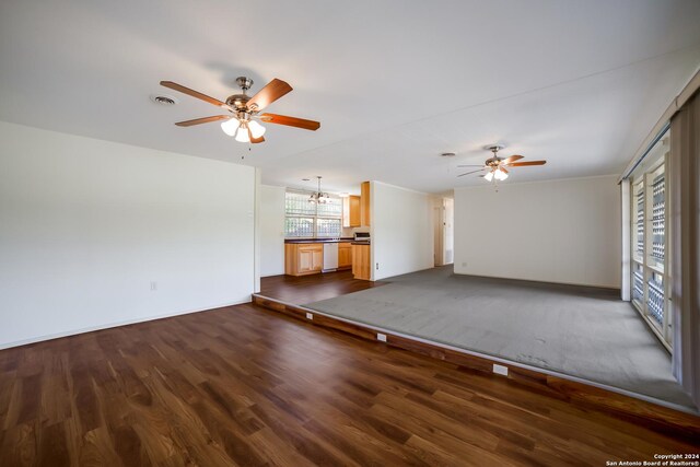 unfurnished living room featuring ceiling fan with notable chandelier and dark wood-type flooring