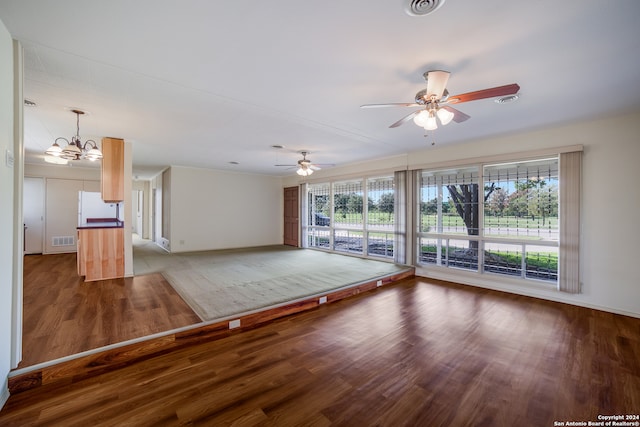 unfurnished room with a healthy amount of sunlight, ceiling fan with notable chandelier, and hardwood / wood-style flooring