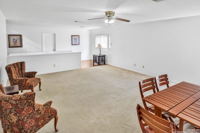 living area with ceiling fan, light colored carpet, and a textured ceiling