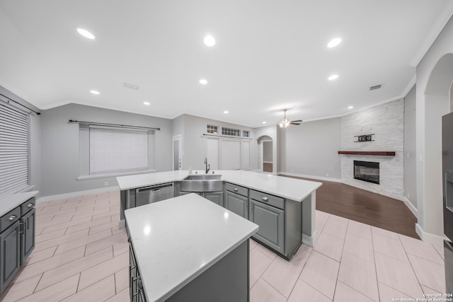 kitchen with a kitchen island, a fireplace, light hardwood / wood-style flooring, ornamental molding, and gray cabinets