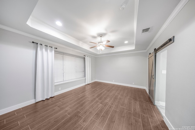 spare room with ceiling fan, crown molding, a barn door, and dark hardwood / wood-style flooring