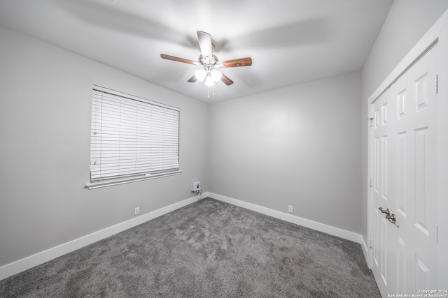 spare room featuring ceiling fan and dark carpet