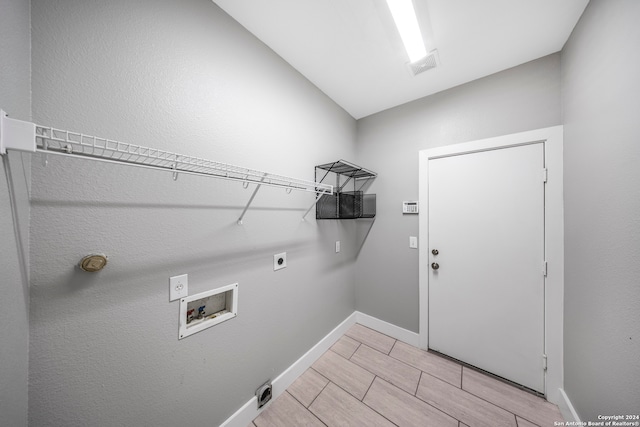 clothes washing area with hookup for a washing machine, light hardwood / wood-style floors, and hookup for an electric dryer