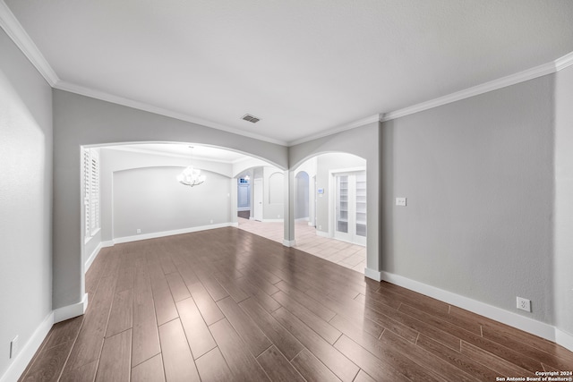 unfurnished living room with ornamental molding, hardwood / wood-style floors, and an inviting chandelier