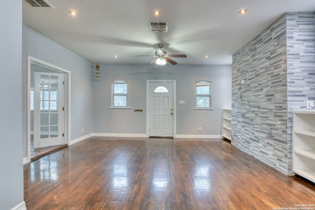 unfurnished living room featuring ceiling fan and dark wood-type flooring