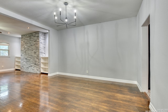 spare room with a notable chandelier and dark hardwood / wood-style flooring