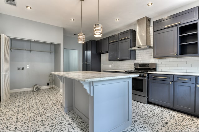 kitchen featuring backsplash, wall chimney exhaust hood, stainless steel gas range, a center island, and decorative light fixtures