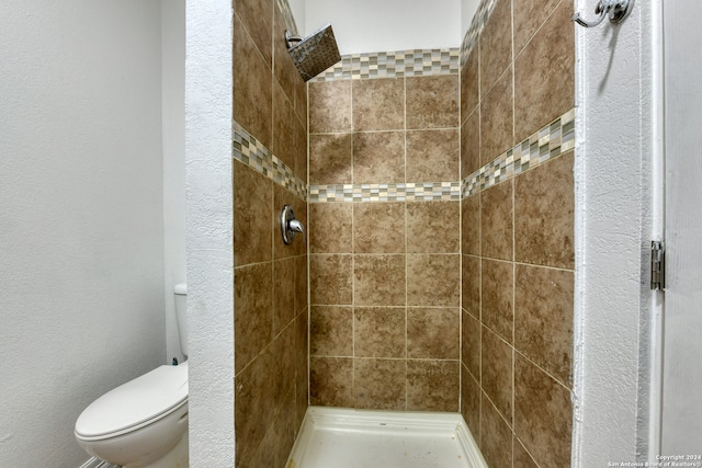 bathroom featuring tiled shower and toilet