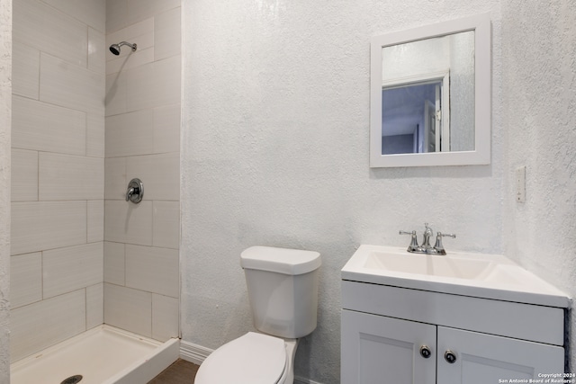 bathroom with vanity, toilet, and tiled shower