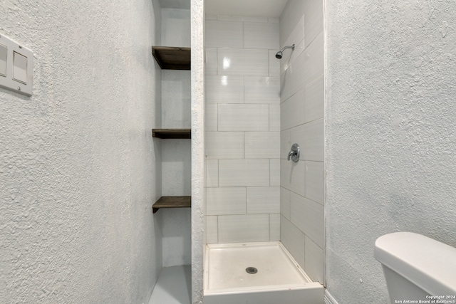 bathroom with a tile shower and toilet