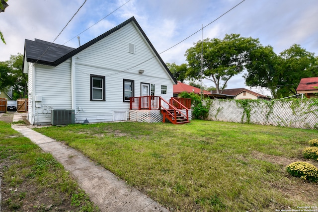 rear view of property featuring a lawn and cooling unit