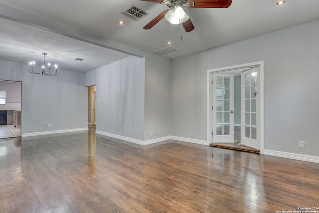 unfurnished room featuring ceiling fan with notable chandelier and dark wood-type flooring