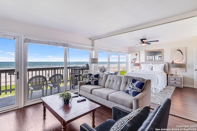 living room featuring a healthy amount of sunlight, a water view, dark hardwood / wood-style flooring, and ceiling fan