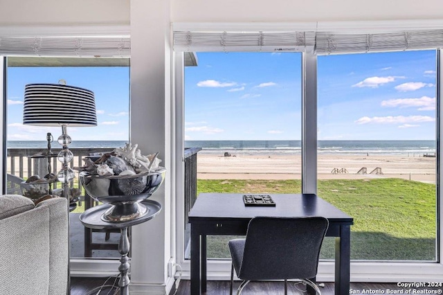 dining room featuring a view of the beach, wood-type flooring, and a water view