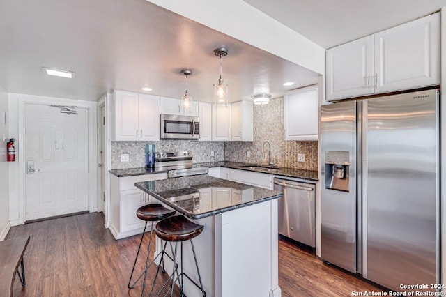 kitchen with hanging light fixtures, dark hardwood / wood-style flooring, stainless steel appliances, and white cabinets