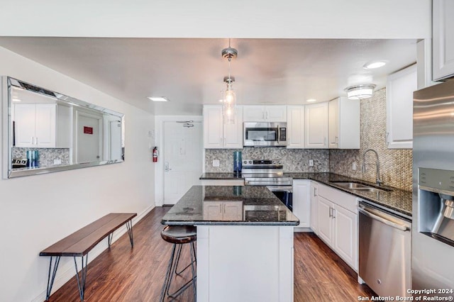 kitchen featuring hanging light fixtures, sink, white cabinetry, stainless steel appliances, and dark hardwood / wood-style flooring