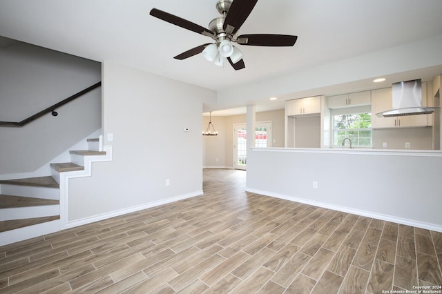 439 Susanwood Dr, San Antonio, TX 78220 - unfurnished living room featuring wood finish floors, ceiling fan with notable chandelier, a sink, baseboards, and stairs
