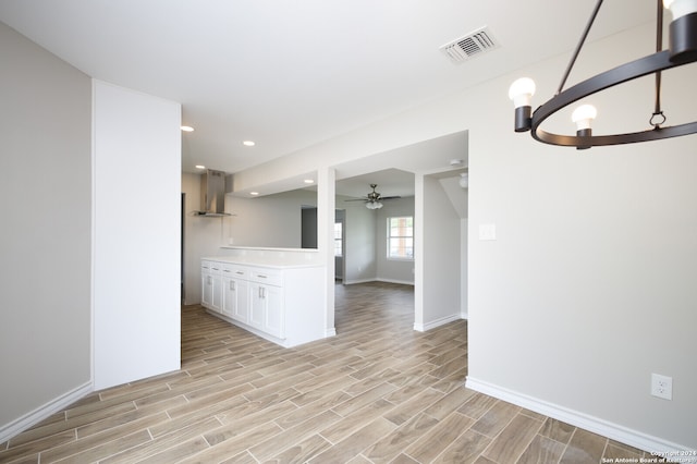 unfurnished room featuring ceiling fan with notable chandelier and light wood-type flooring