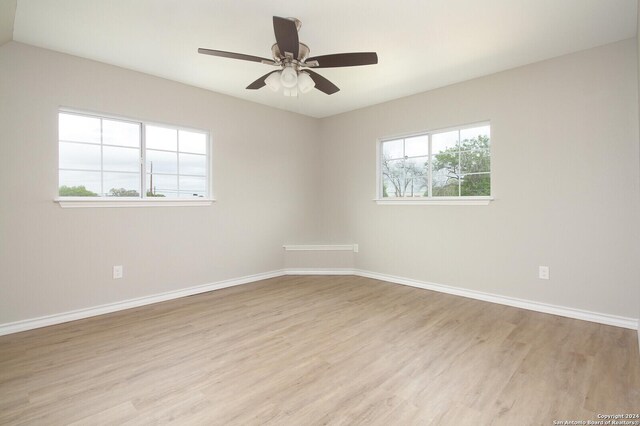 empty room with ceiling fan and light hardwood / wood-style flooring