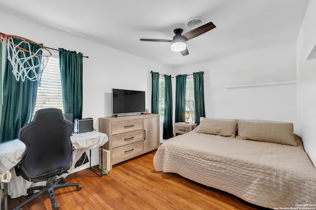 bedroom with multiple windows, hardwood / wood-style floors, and ceiling fan