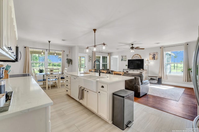 kitchen featuring ceiling fan with notable chandelier, white cabinets, hanging light fixtures, and a healthy amount of sunlight