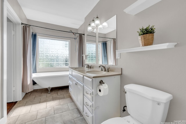 bathroom featuring a tub, toilet, vanity, and tile patterned floors