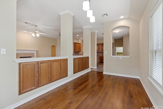 kitchen with ceiling fan, ornate columns, decorative light fixtures, dark wood-type flooring, and vaulted ceiling