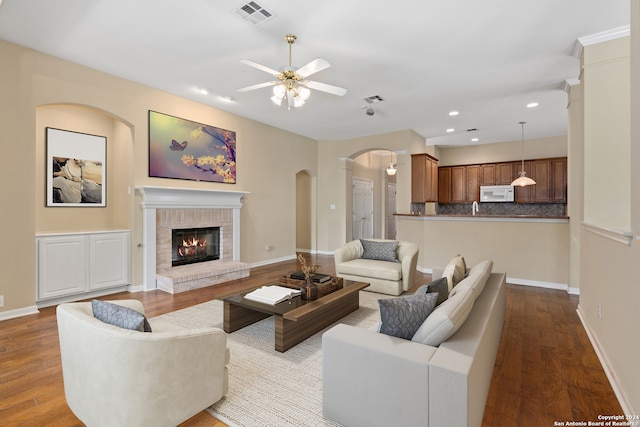 living room featuring a brick fireplace, light wood-type flooring, and ceiling fan