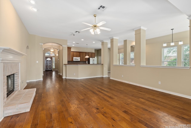 unfurnished living room featuring a fireplace, dark wood-type flooring, and ceiling fan