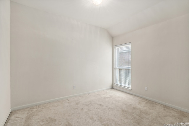 carpeted empty room featuring vaulted ceiling