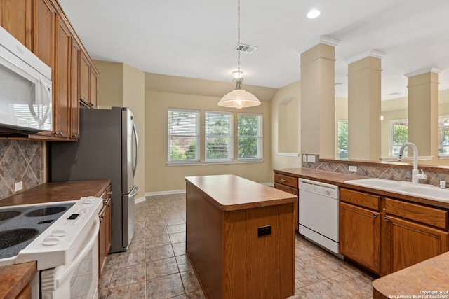 kitchen with a wealth of natural light, ornate columns, white appliances, and a kitchen island