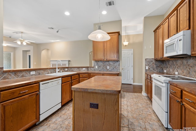 kitchen with ceiling fan, white appliances, a kitchen island, decorative light fixtures, and decorative backsplash