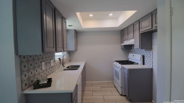 kitchen featuring gray cabinets, a raised ceiling, sink, and white gas range oven