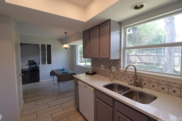 kitchen with decorative backsplash, white dishwasher, pendant lighting, and sink