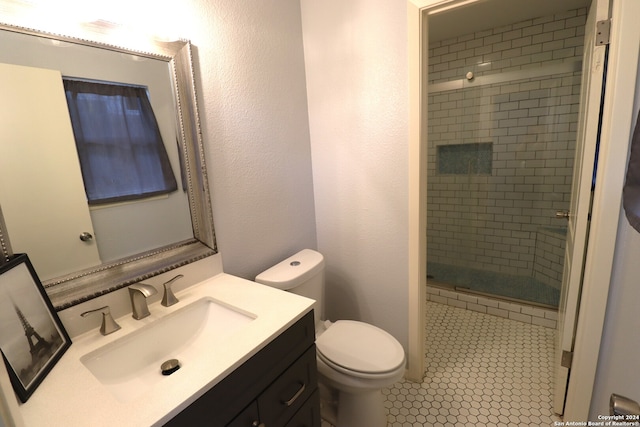 bathroom featuring tile patterned flooring, vanity, toilet, and an enclosed shower